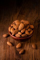 In the foreground, a group of shelled almonds in an earthenware bowl.