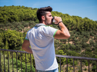 Obraz premium Handsome man drinking american coffee outdoor in summer