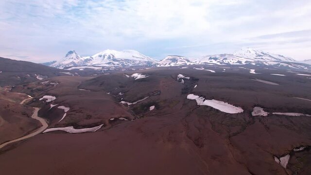 Aerial show approaching snow covered mountains in Iceland. Dramatic landscape, partly cloudy sky. 