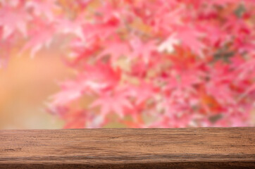 Naklejka na ściany i meble Mockup wood table for product display with blurred red and pink maple leaves background.
