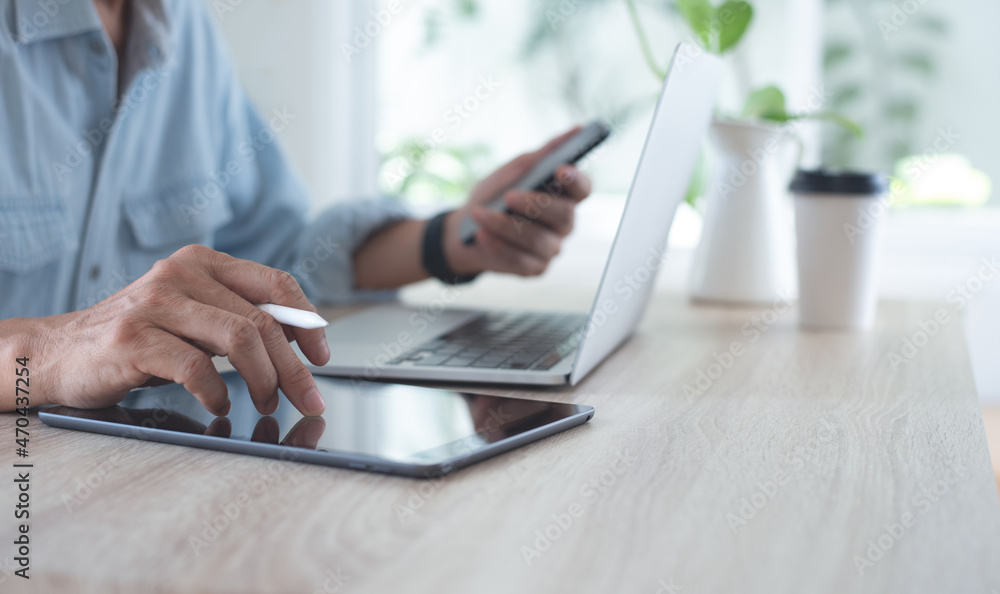 Poster casual business man using digital tablet and mobile phone during working on laptop computer on table