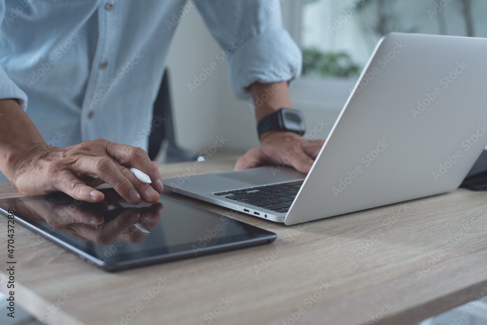 Poster close up of business man hand using digital tablet and working on laptop computer surfing the intern
