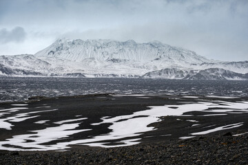 Autumn snowfall in Iceland highlands. Colorful Landmannalaugar mountains under snow cover in autumn, Iceland. Lava fields of volcanic sand in the foreground.