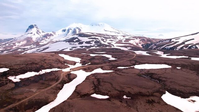 Iceland aerial shot at Kerlingarfjöll in highlands. Epic snowy mountains with dirt road leading to it. 