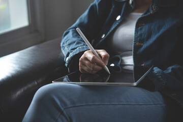 Close up of casual business woman hand holding and using stylus pen on digital tablet via mobile...