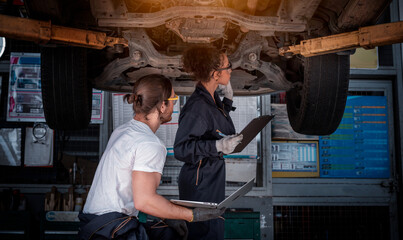 Car mechanic technician under checking the car suspension  by see detail in note book on hand for...