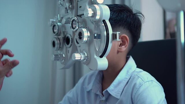 Boy doing eye test checking examination with optometrist in optical shop, Optometrist doing sight testing for child patient in clinic