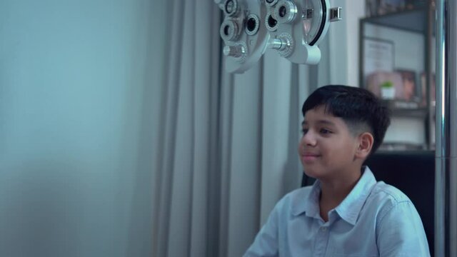 Boy doing eye test checking examination with optometrist in optical shop, Optometrist doing sight testing for child patient in clinic