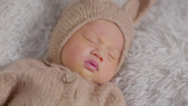 happy newborn baby weaing cute rabbit costume lying sleep on grey carpet background comfortable and safety.Cute Asian infant sleeping and napping on baby bed.Newborn Baby Easter Day Concept