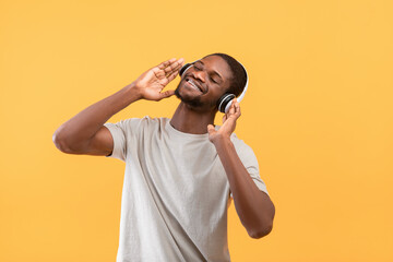 Best music. Happy african american guy in wireless headphones enjoying his favorite songs and smiling
