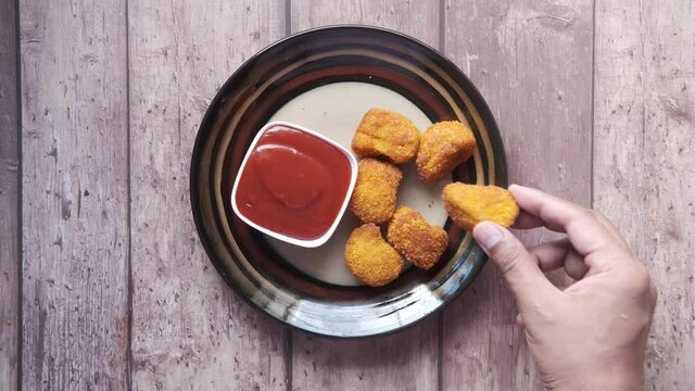 hand pick chicken nugget and sauce on table 