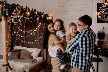 Fototapeta premium Beautiful young family near a Christmas tree on Christmas Eve