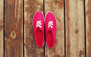 Summer image of pink gumshoes on a wooden table or floor background, top view