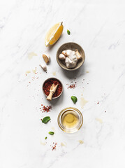 Preparation salad dressings, - chili spices, oil, lemon juice and garlic on white marble background.