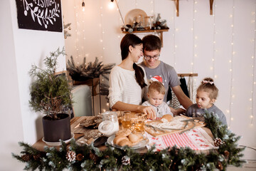 Beautiful family preparing homemade cakes on the christmas table against the backdrop of the decorations for the holiday