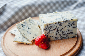 Sliced cheese with blue mold on a wooden cutting board. Cheese composition. Cheese texture with mold.