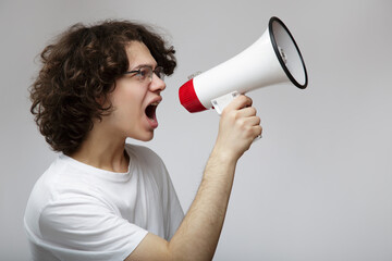 young teenage man shouts into a megaphone. Gray background