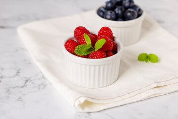 Raspberries and blueberries for breakfast on a white napkin