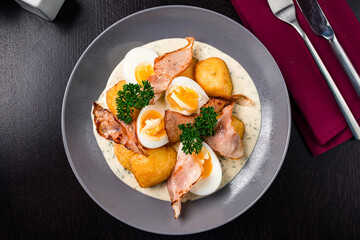 Colorful yellow hard boiled free range eggs in a creamy and mustard sauce served garnished with fresh herbs top view, flat lay