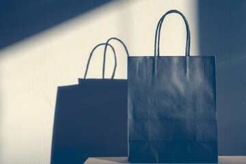 Selective focus of black grey shopping bag on wooden table, Paper bag with light and shadow on...