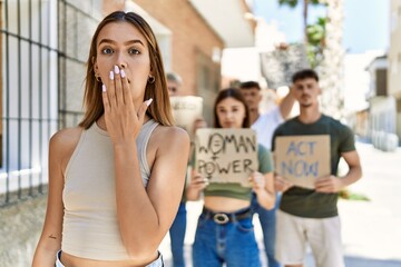 Group of people protesting and giving slogans at the street covering mouth with hand, shocked and afraid for mistake. surprised expression