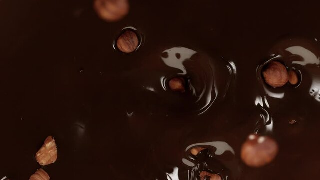 Super slow motion of falling hazelnuts into dark hot chocolate. Filmed on cinema high speed camera, 1000fps.