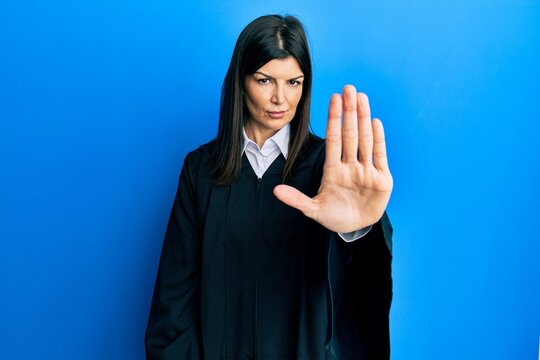 Young hispanic woman wearing judge uniform doing stop sing with palm of the hand. warning expression with negative and serious gesture on the face.