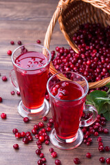 Two glasses with organic cranberry juice with lot of berries on wooden background. Healthy lifestyle concept