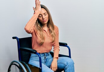 Beautiful hispanic woman sitting on wheelchair surprised with hand on head for mistake, remember...