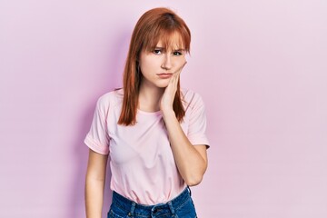 Redhead young woman wearing casual pink t shirt touching mouth with hand with painful expression because of toothache or dental illness on teeth. dentist