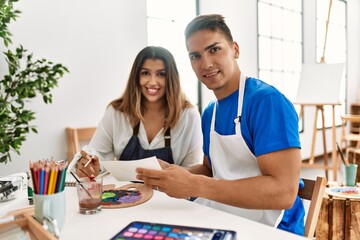 Obraz premium Two students smiling happy painting sitting on the table at art school.