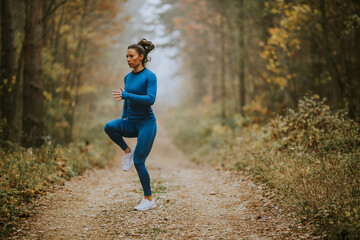 Young woman running having exercise on forest trail at autumn