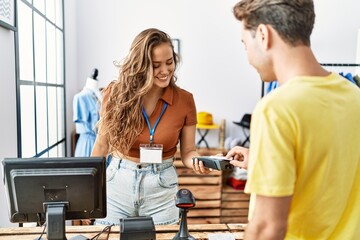 Man and woman paying purchase using credit card and data phone at clothing store