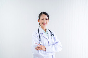 Smiling female doctor in lab coat crossing arms against white background