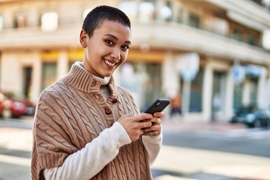 Young hispanic woman with short hair smiling happy using smartphone