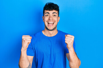 Young hispanic man wearing casual blue t shirt celebrating surprised and amazed for success with arms raised and open eyes. winner concept.