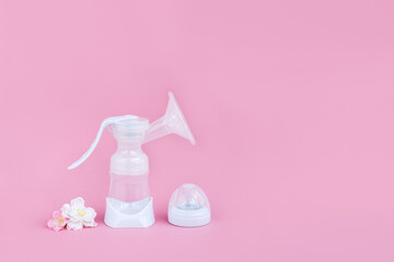 Breast pump and flowers on a pink background. Breastfeeding concept. Copy space