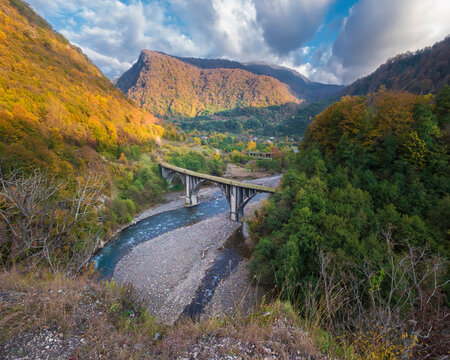 Beautiful arched bridge in the autumn mountains over the river