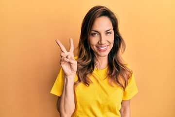 Young latin woman wearing casual clothes showing and pointing up with fingers number two while smiling confident and happy.