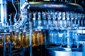 Automatic filling machine pours water into plastic PET bottles at modern beverage plant.
