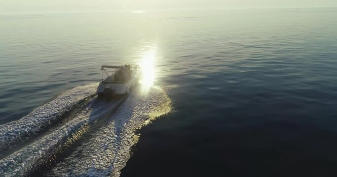 A drone shot of a happy family on a summer vacation driving a luxury boat on the high seas in the early morning