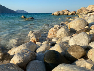 Large beautiful natural round stones and pebbles washed by water on the seashore or ocean against the backdrop of mountains