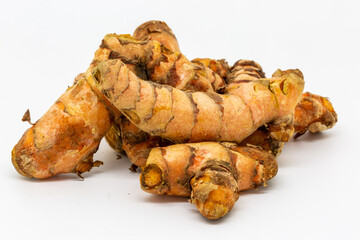 A studio photograph of whole turmeric root