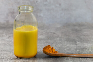 Turmeric powder and a turmeric latte against a grey background