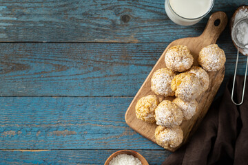 Homemade coconut cookies on a serving board on a blue wooden culinary background. Top view