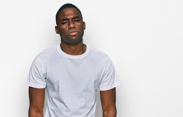 Young african american man wearing casual white t shirt looking sleepy and tired, exhausted for fatigue and hangover, lazy eyes in the morning.