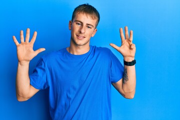 Young caucasian man wearing casual blue t shirt showing and pointing up with fingers number nine...