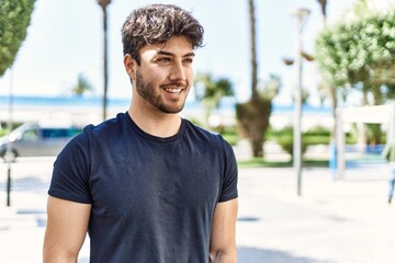 Young hispanic man smiling happy standing at the city.