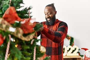 Young african american man smiling confident decorating christmas tree at home