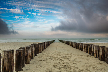 Sandy beach at Burgh-Haamstede in the Dutch province of Zeeland with a double row of posts of beach...